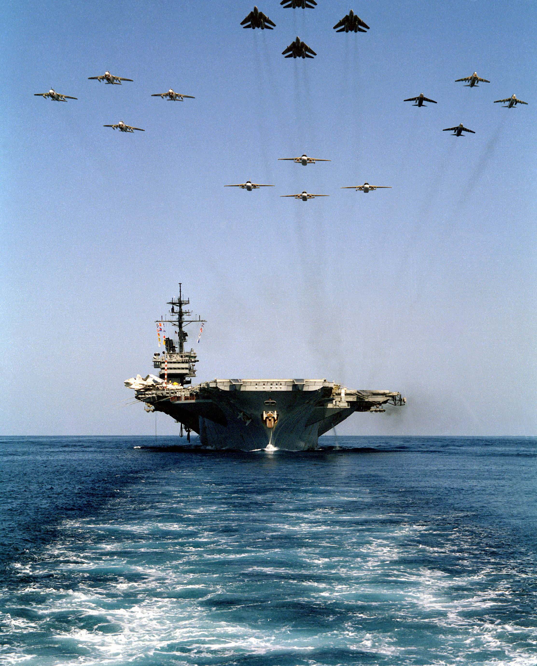 A bow view of the aircraft carrier USS AMERICA (CV-66) underway as16 aircraft from Carrier Air Wing One (CVW-1) fly overhead.